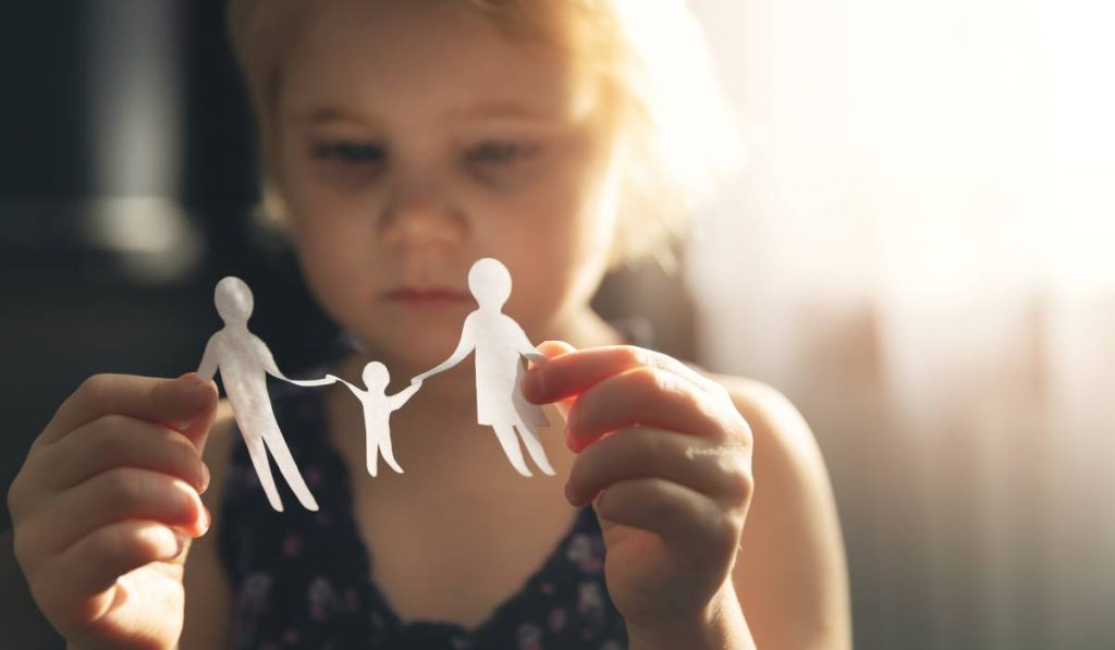 A child holding a paper cutout of her family