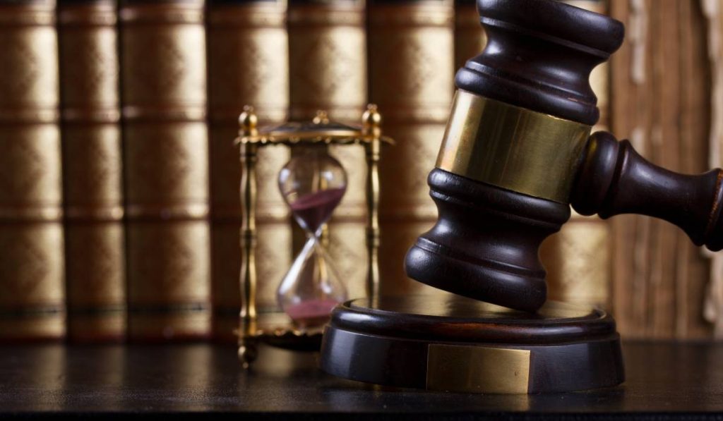 Judge's gavel on a wooden table with books and an hourglass to show contested divorce timeline.