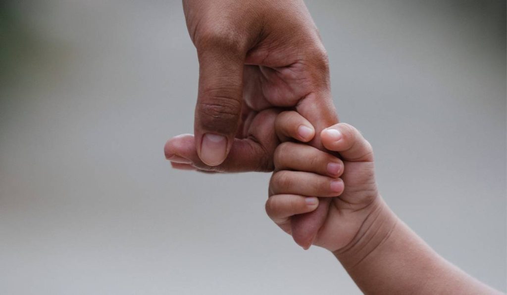 A parent holding their child's hand.