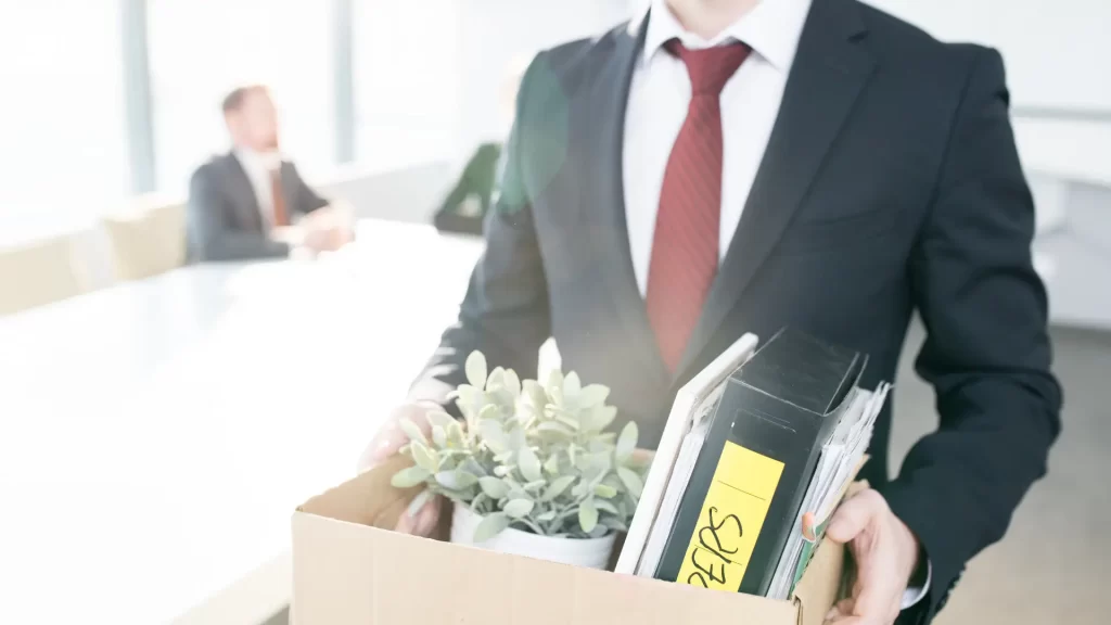 An employee walking out of the office with a box full of personal items