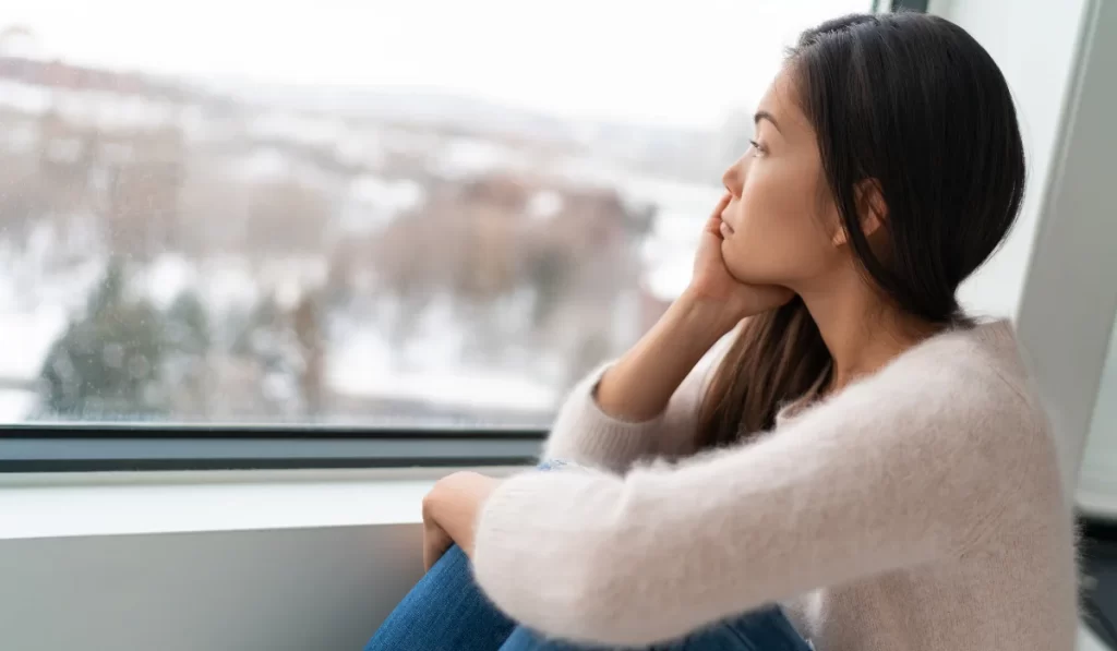 a person is looking out of the window with their hand resting on their chin