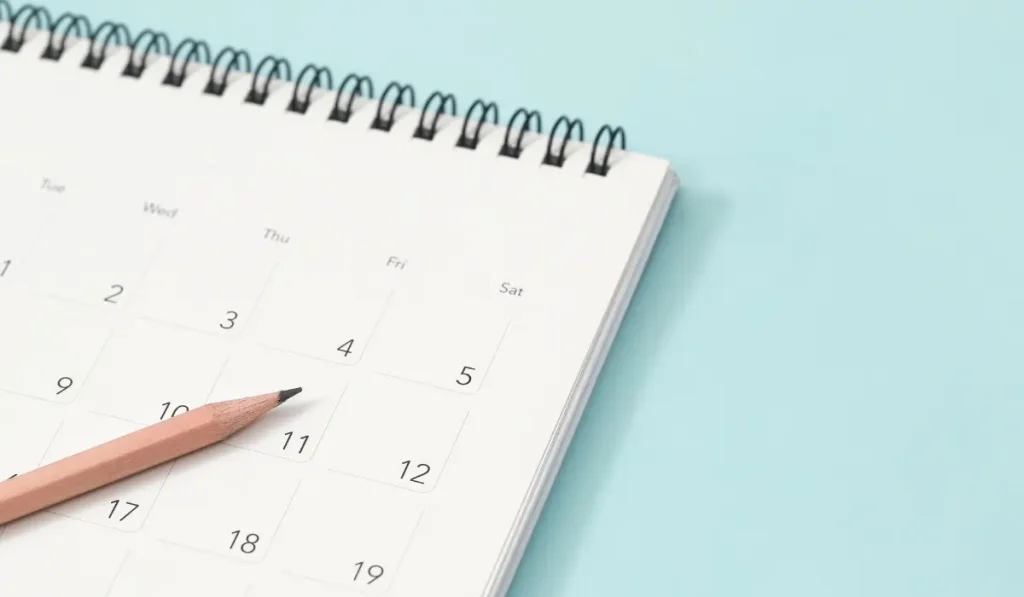 Calendar and pencil on a plain background.