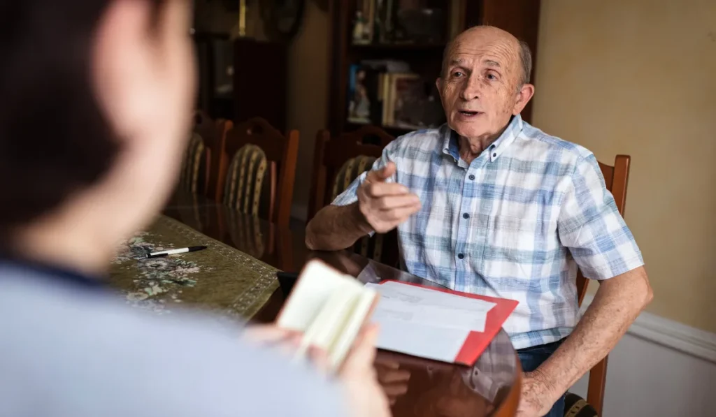 Older man speaking with a lawyer in an office.